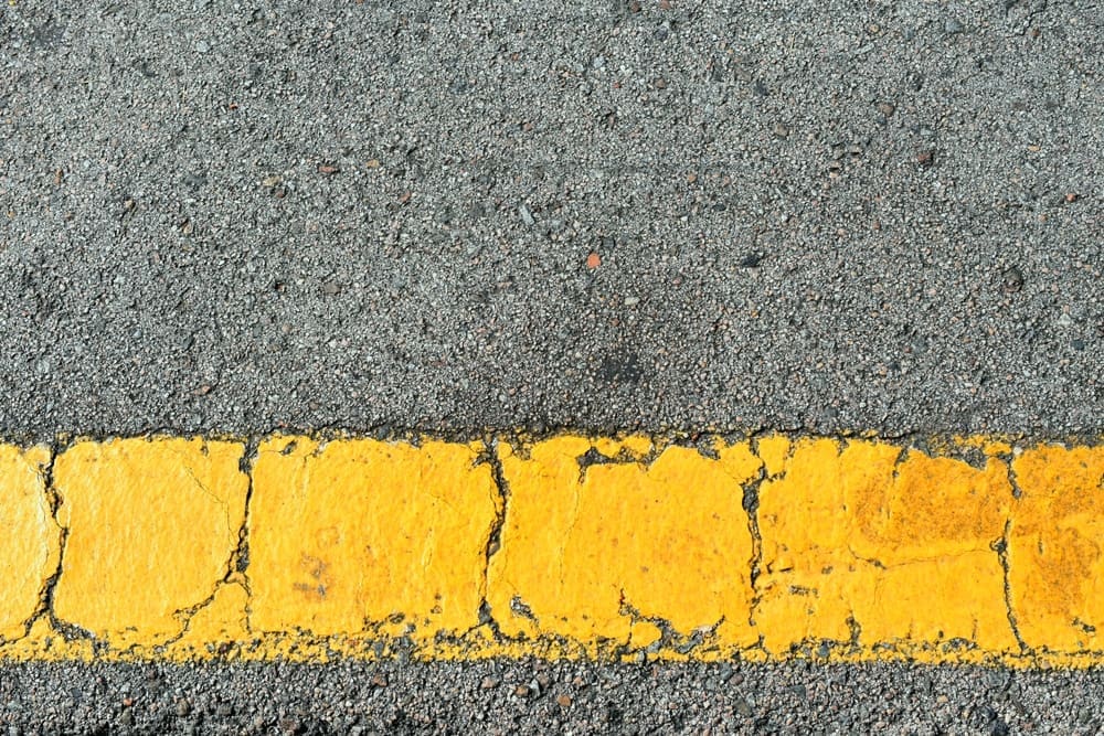 Houston Businesses: Is Your ADA Striping Up to Code? 4 Yellow strip of old road markings on gray asphalt.